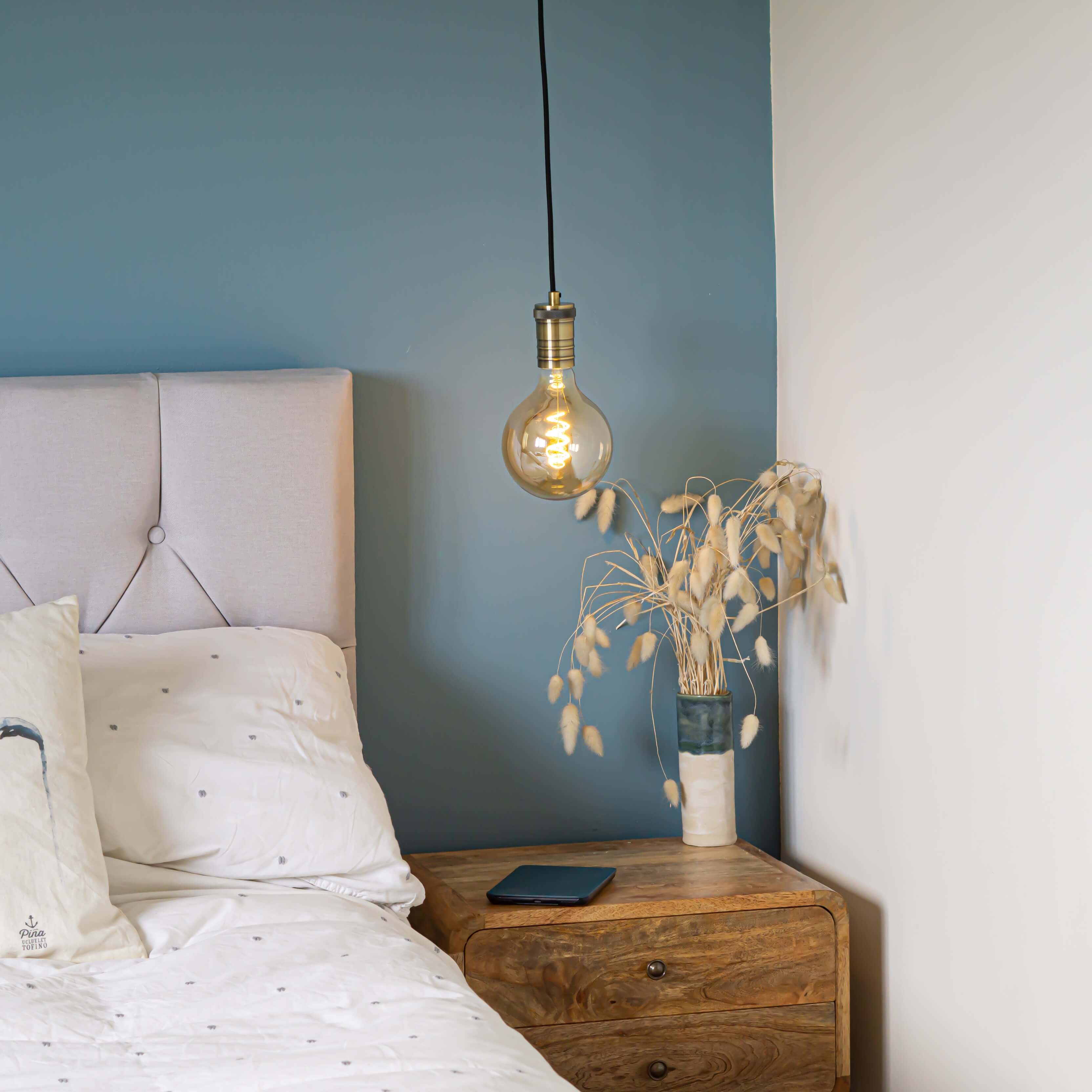 antique bronze pendant light and straight cable with sophia bulb hanging above the bedside table