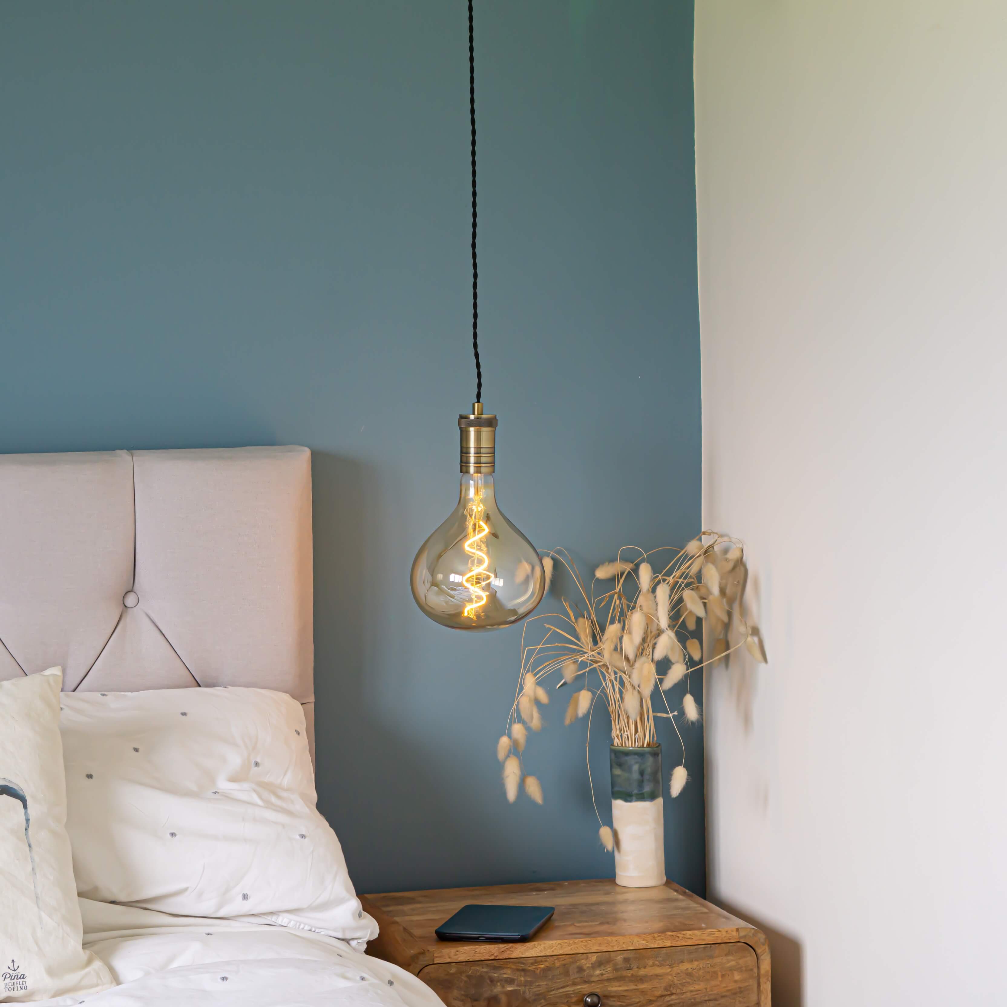 antique bronze pendant light and twisted cable with olivia bulb hanging above the bedside table