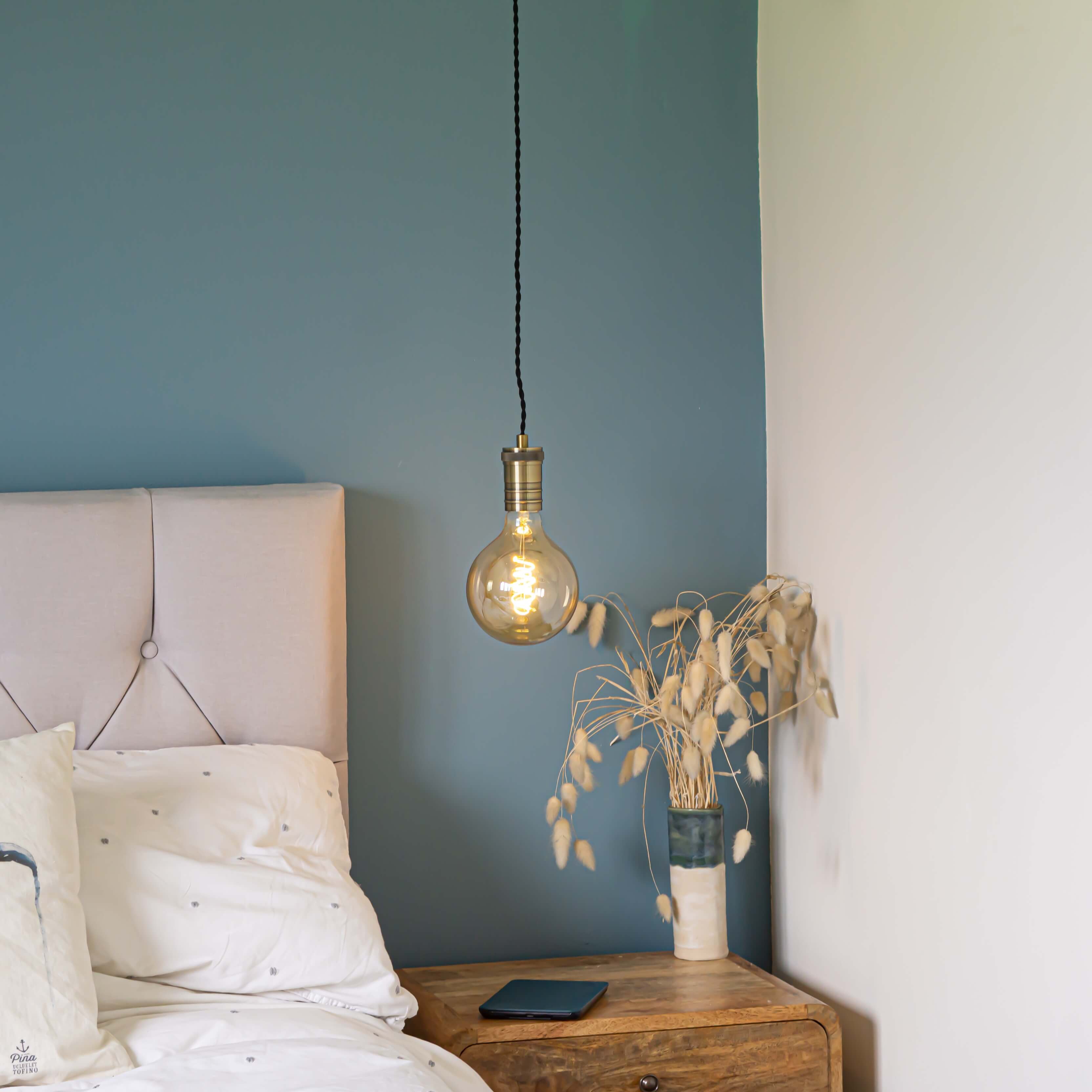 antique bronze pendant light and twisted cable with sophia bulb hanging above the bedside table
