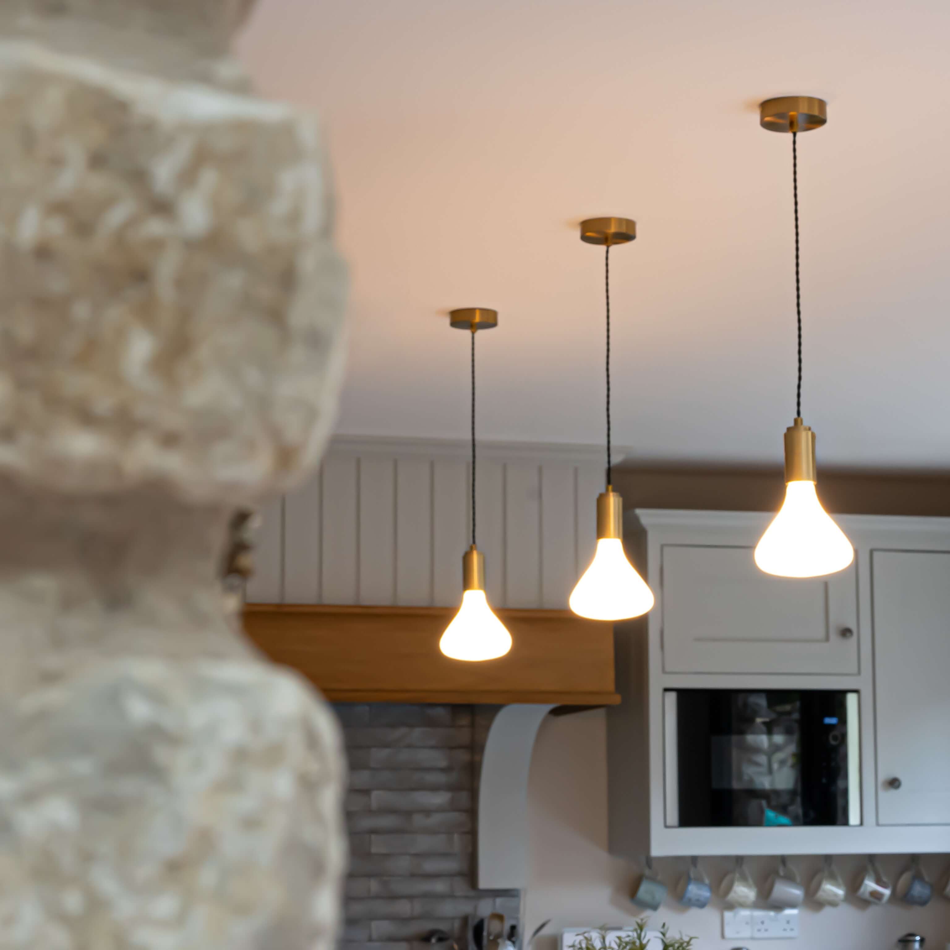 Astrid brass pendant light behind wall