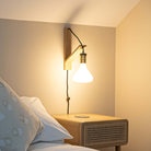 astrid plug in antique brass wall light with straight cable mounted by a bed