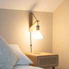 astrid plug in antique brass wall light with twisted cable mounted by a bed