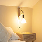 astrid plug in antique brass wall light with straight cable mounted by a bed