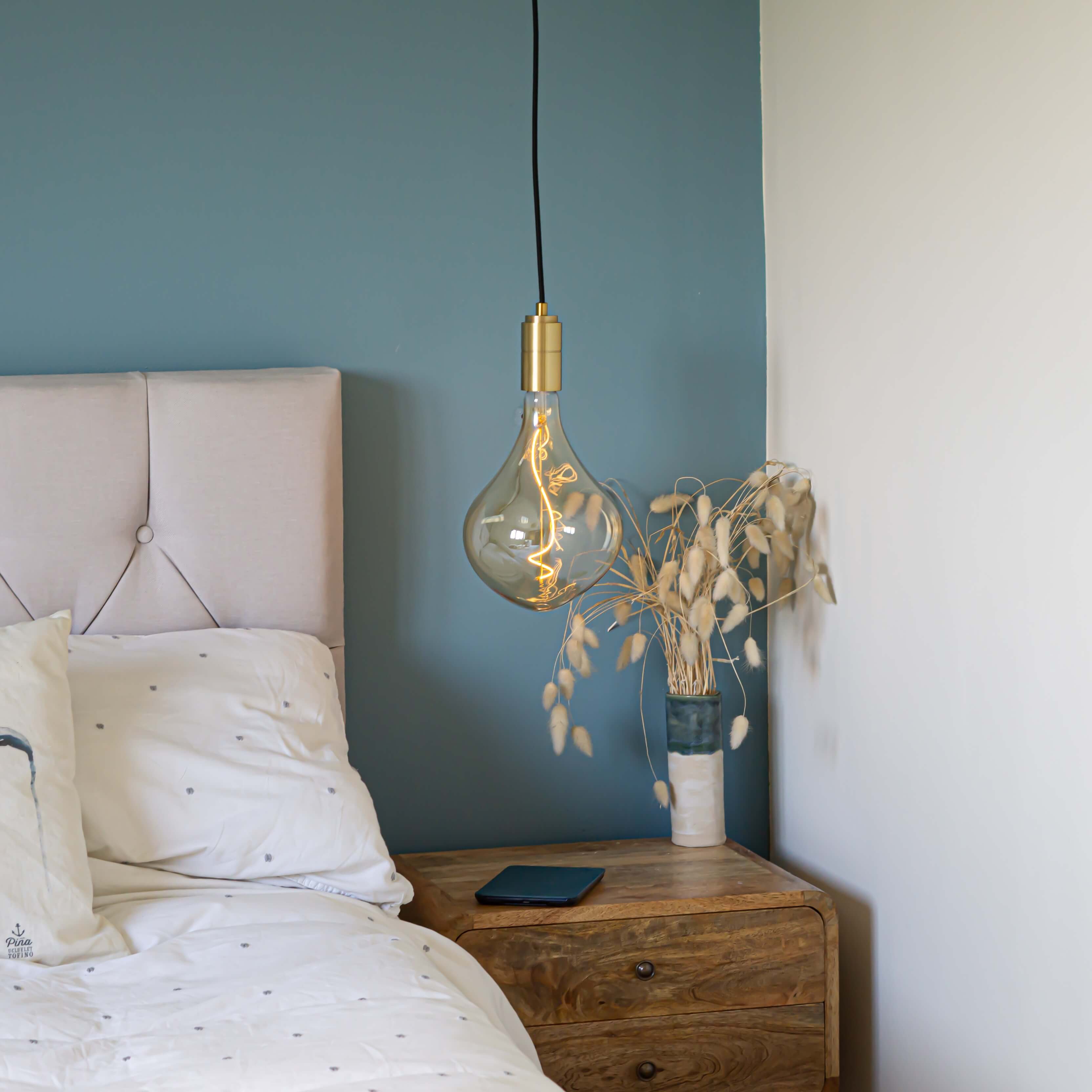 brass pendant light and straight cable with celeste bulb hanging above the bedside table in the bedroom