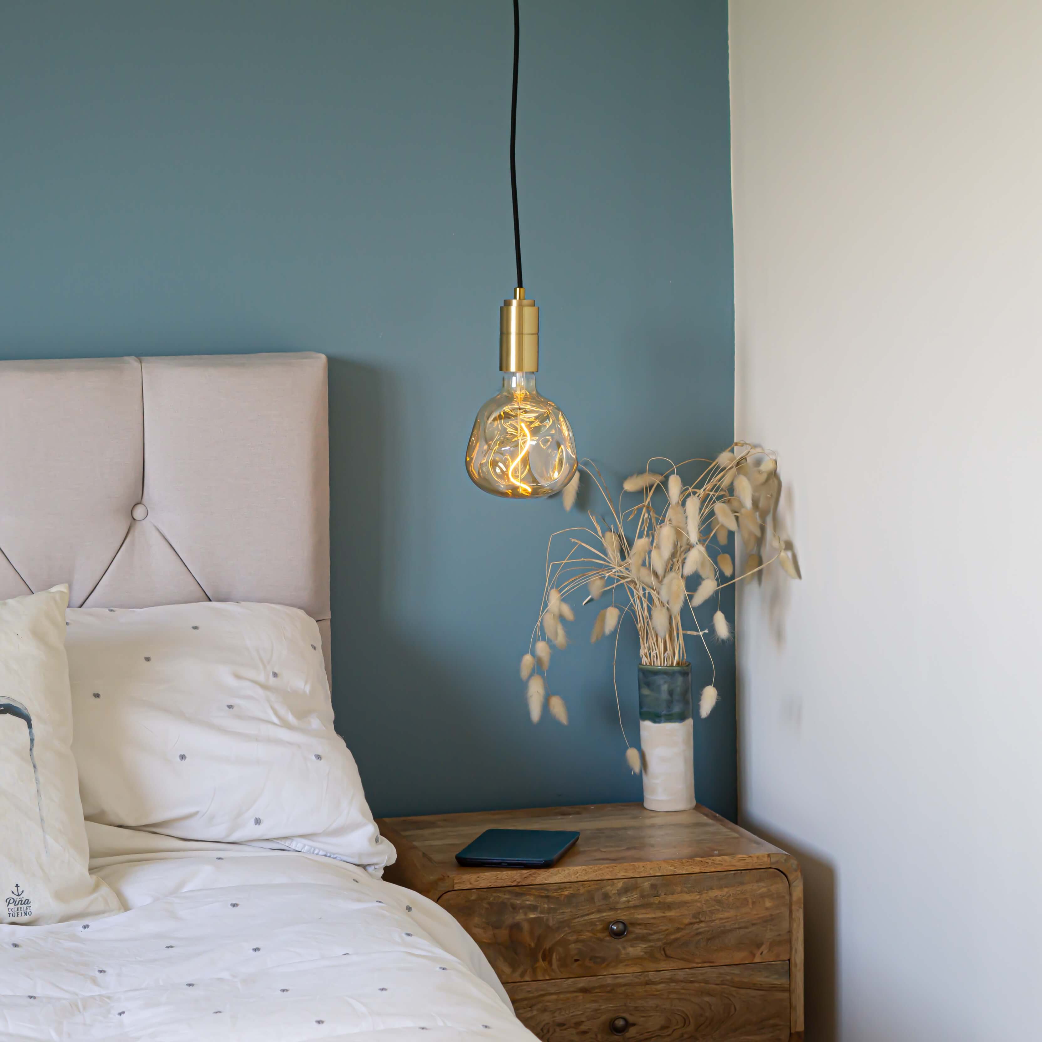 brass pendant light and straight cable with isabella bulb hanging above the bedside table