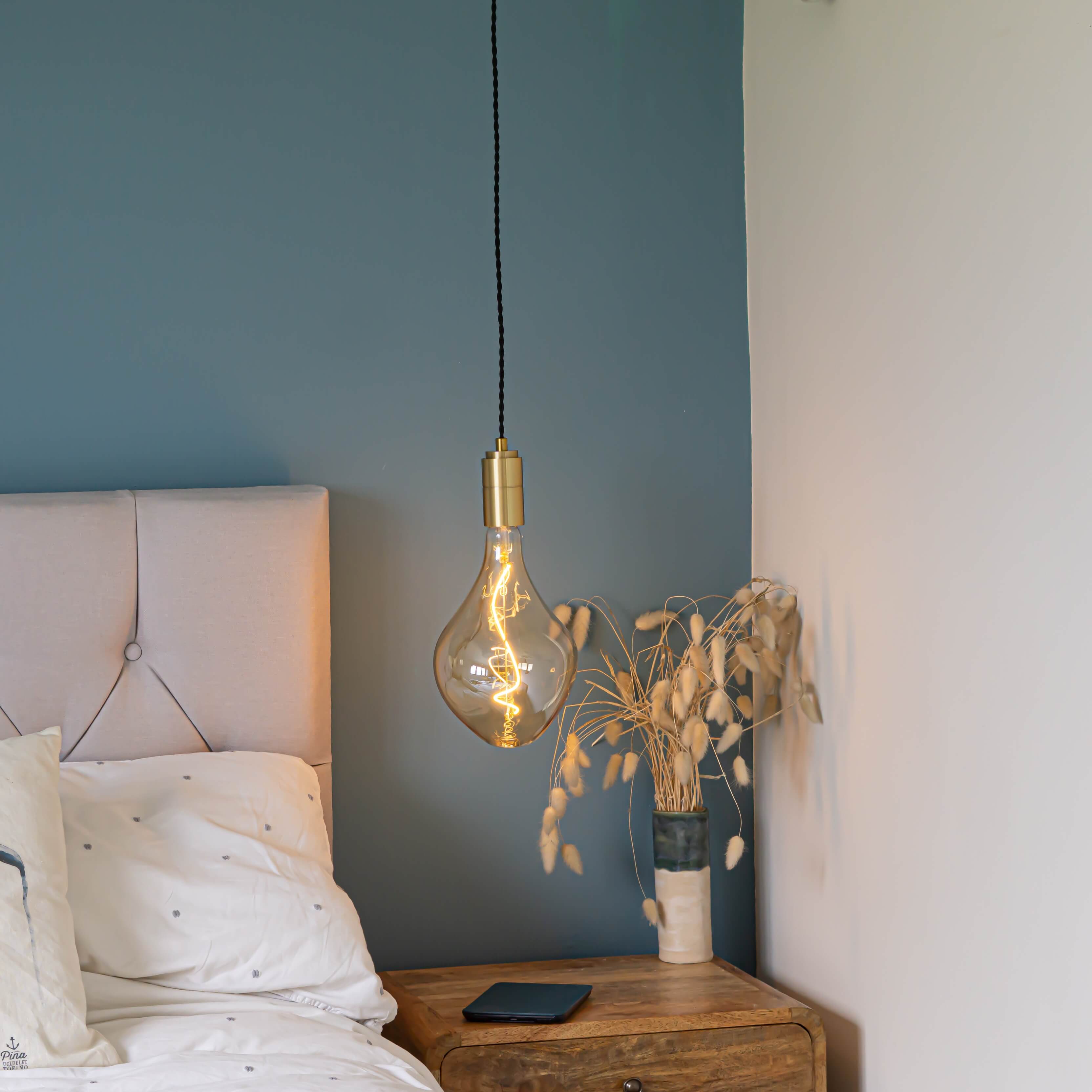 brass pendant light and twisted cable with celeste bulb hanging above the bedside table in the bedroom