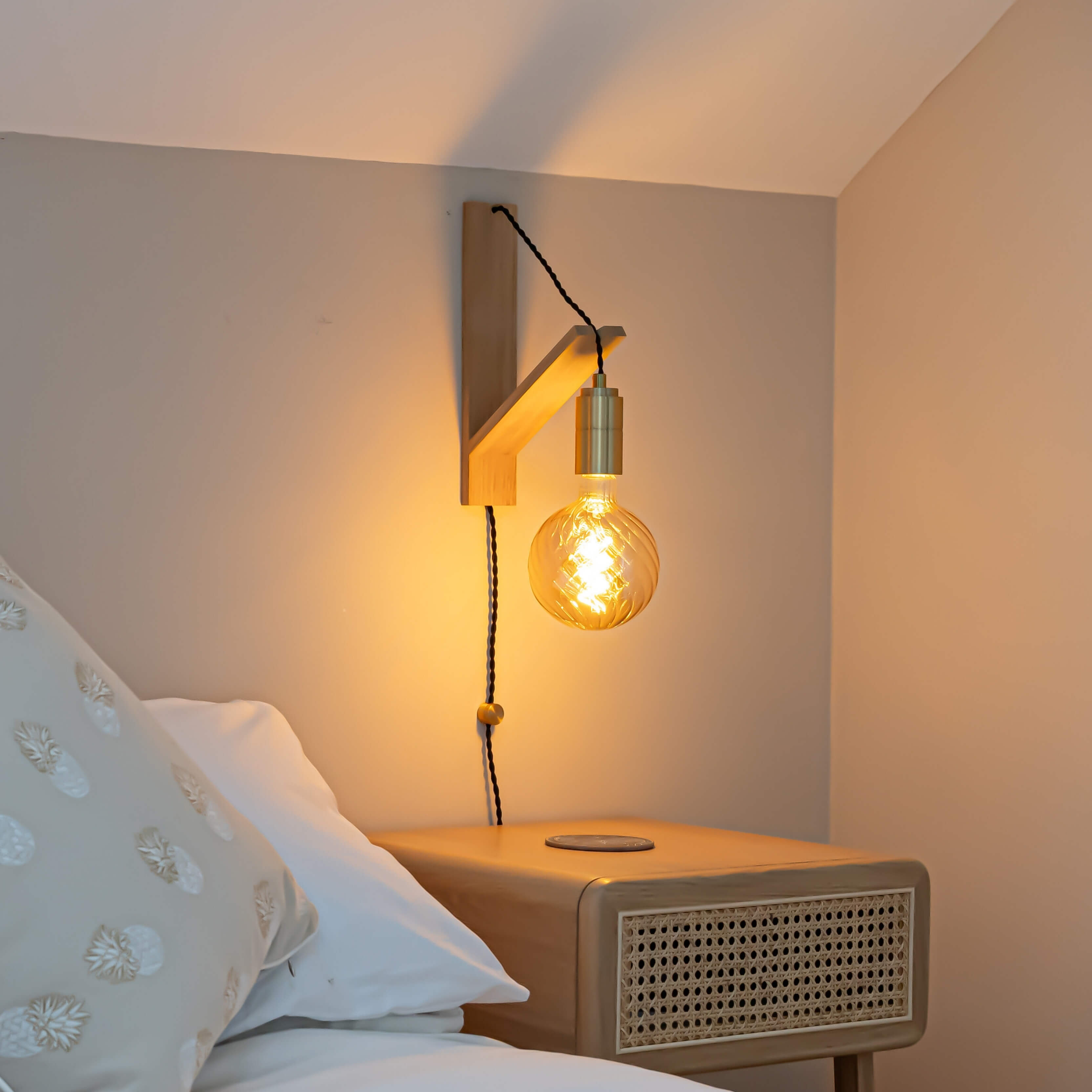 brass plug in antique brass wall light with straight cable mounted by a bed