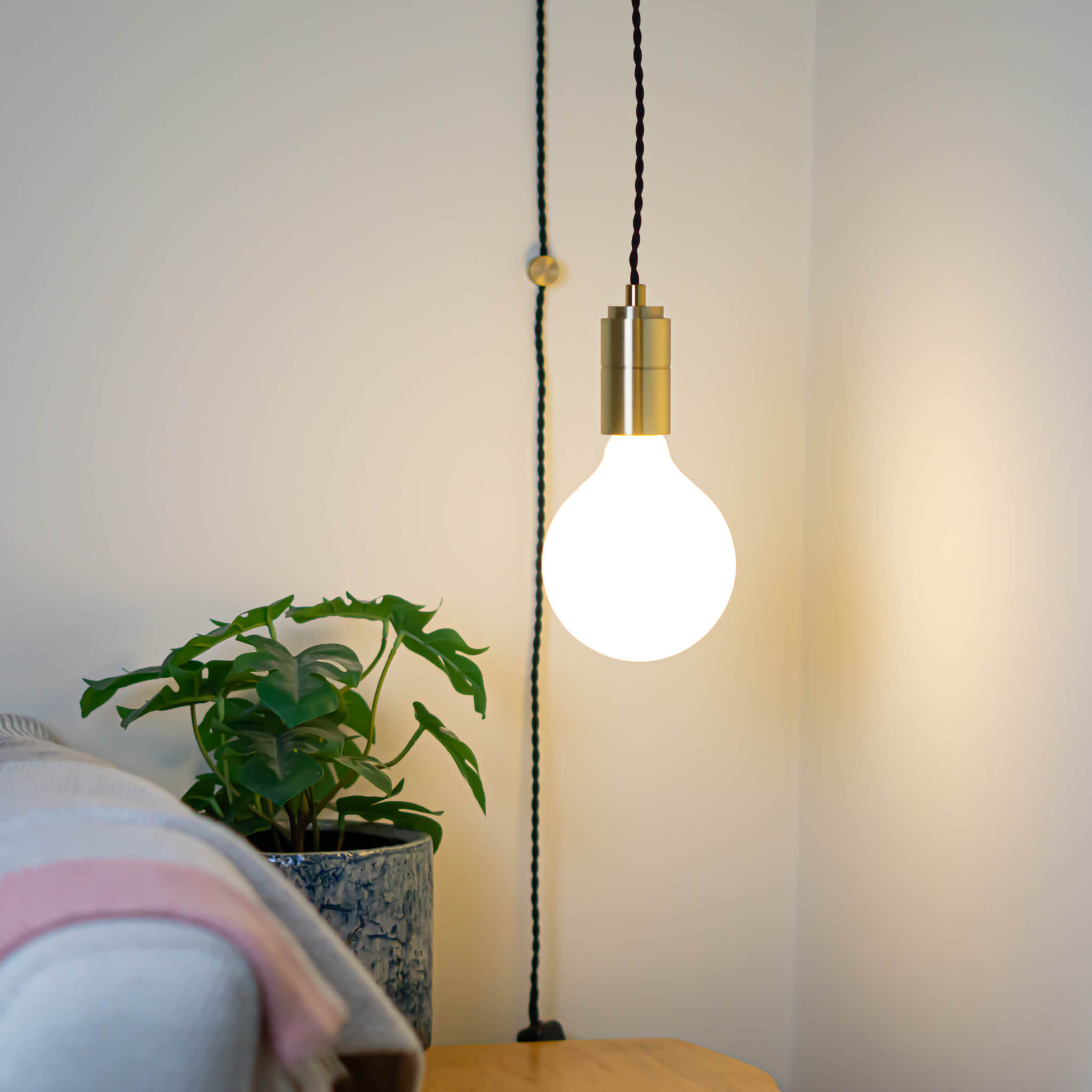 brass plug in pendant light and twisted cable luna bulb in living room on