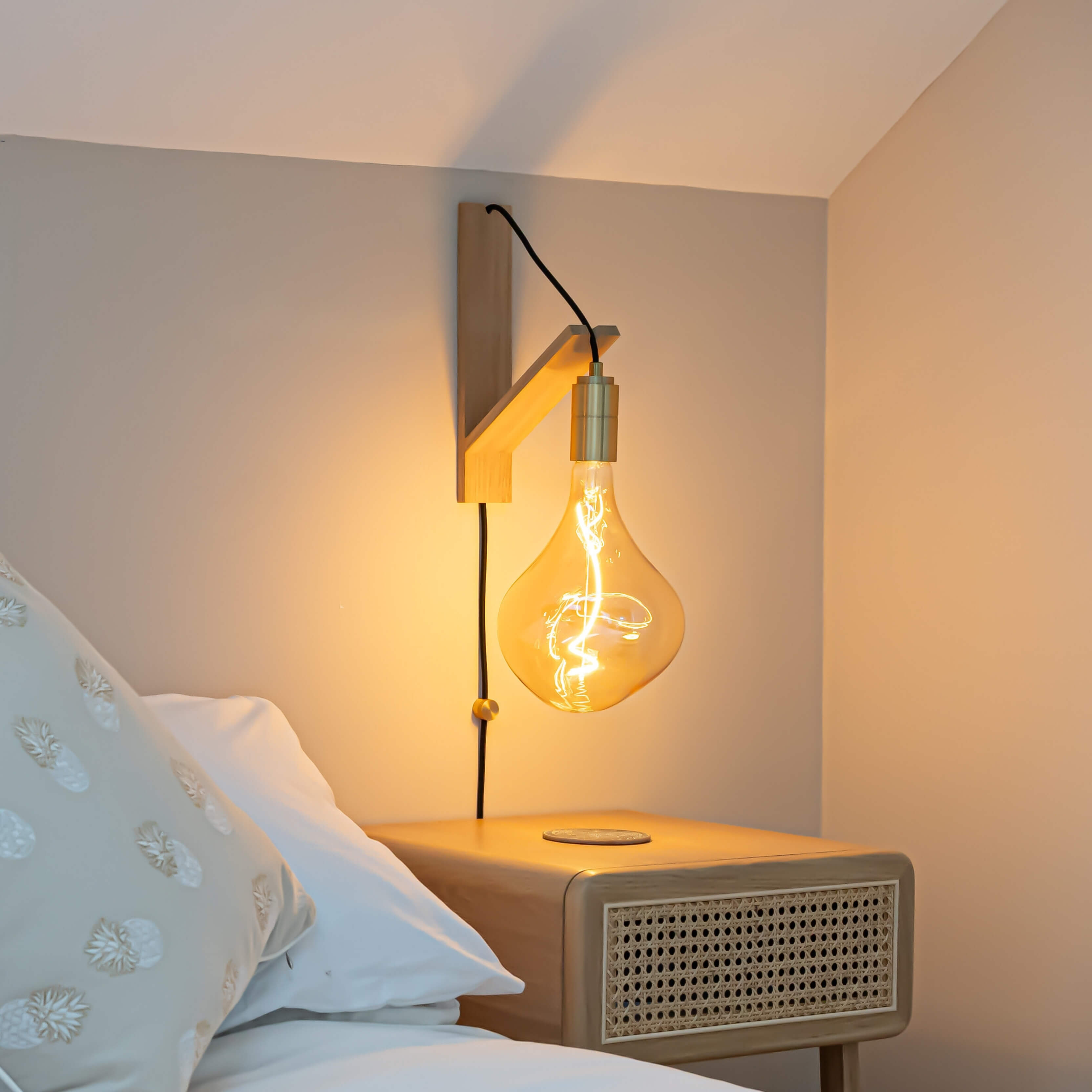 celeste plug in brass wall light with straight cable mounted by a bed