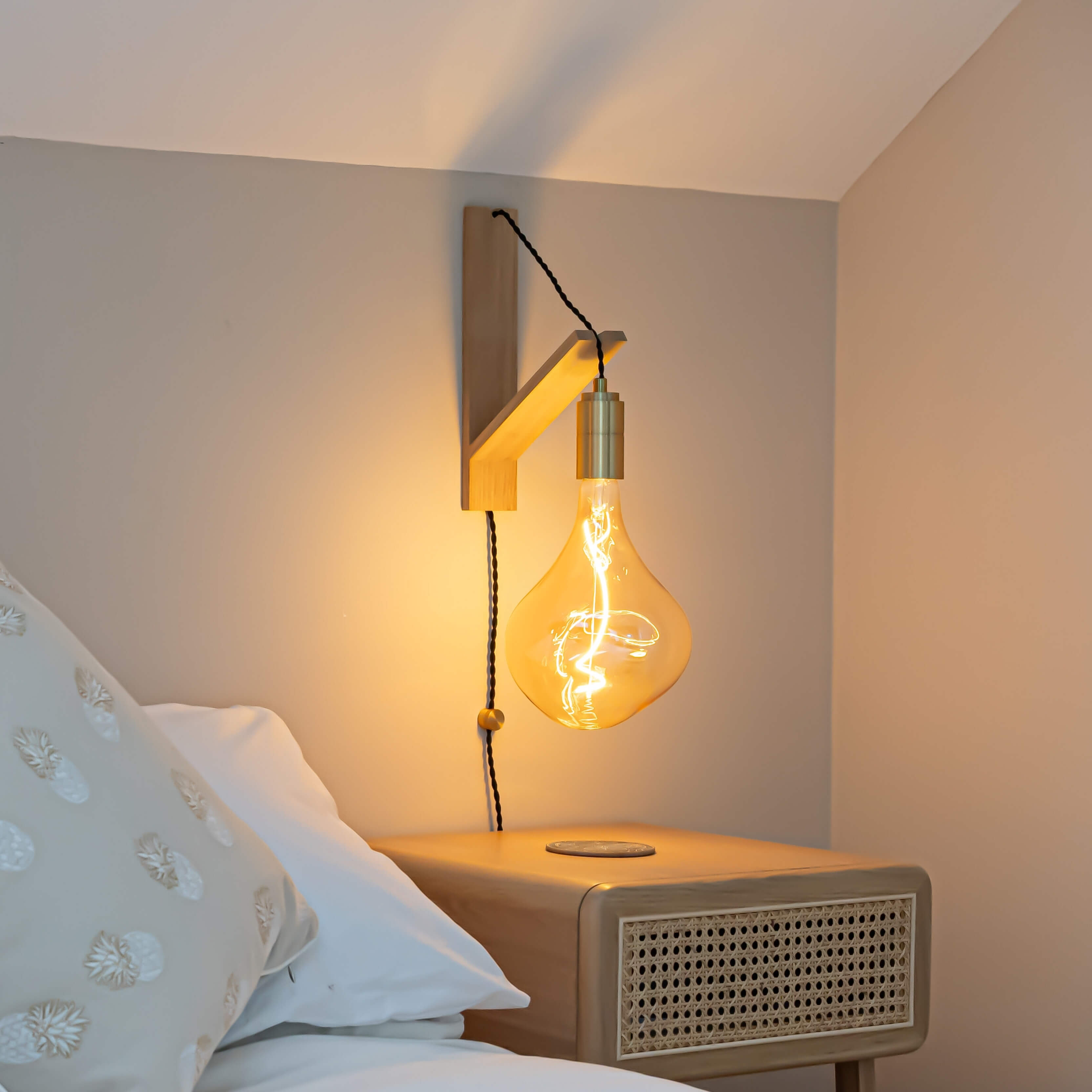 celeste plug in brass wall light with twisted cable mounted by a bed