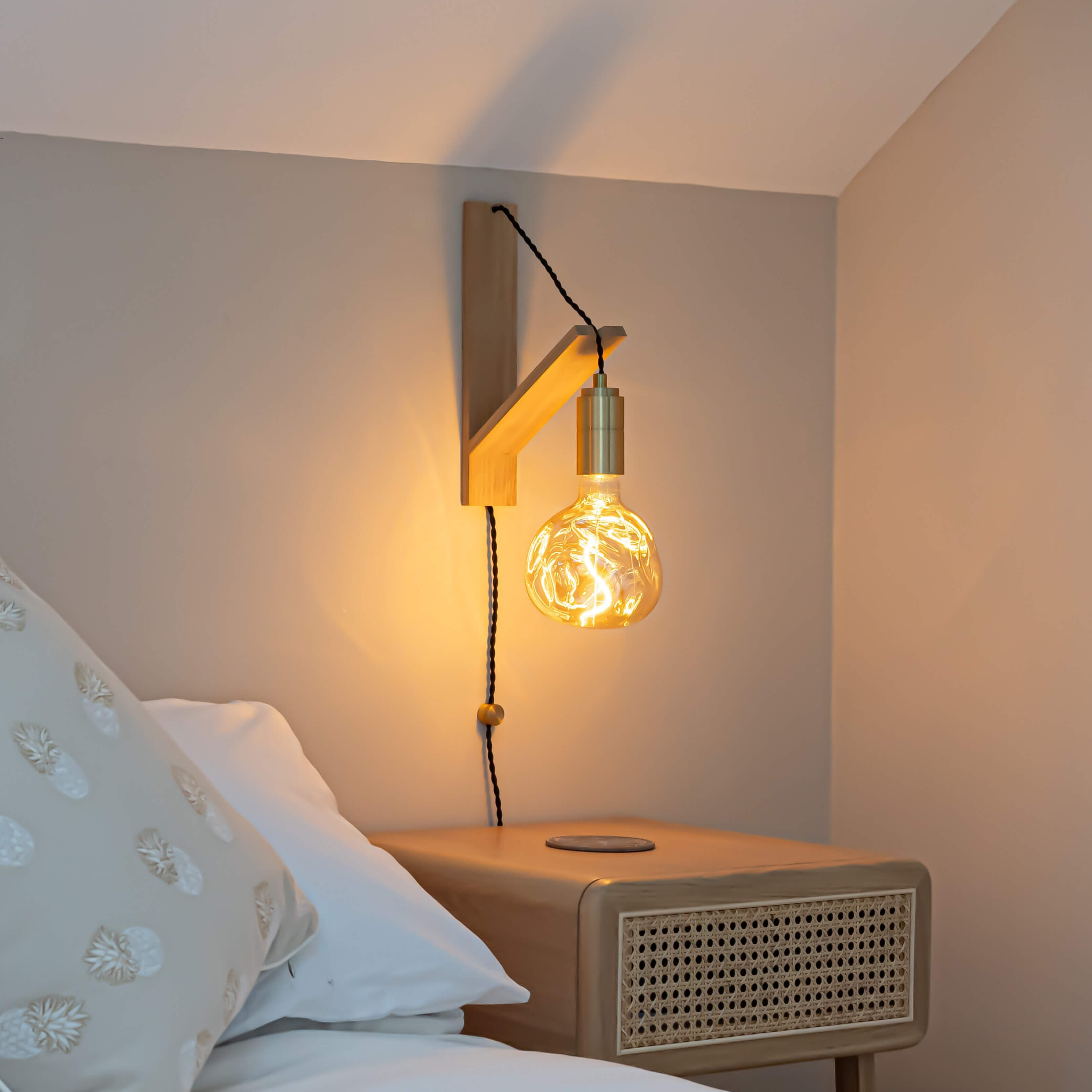 isabella plug in brass wall light with twisted cable mounted by a bed