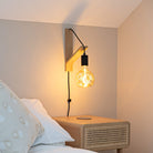 isabella plug in antique brass wall light with twisted cable mounted by a bed