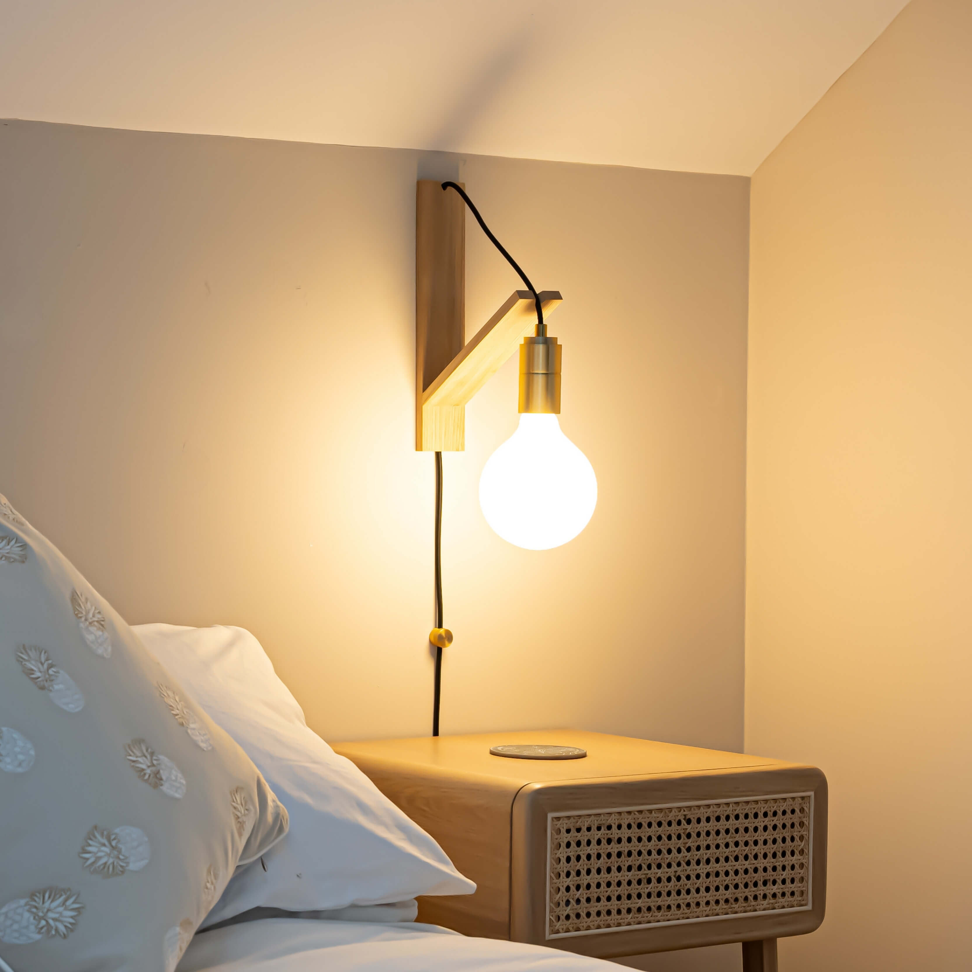 luna plug in brass wall light with straight cable mounted by a bed
