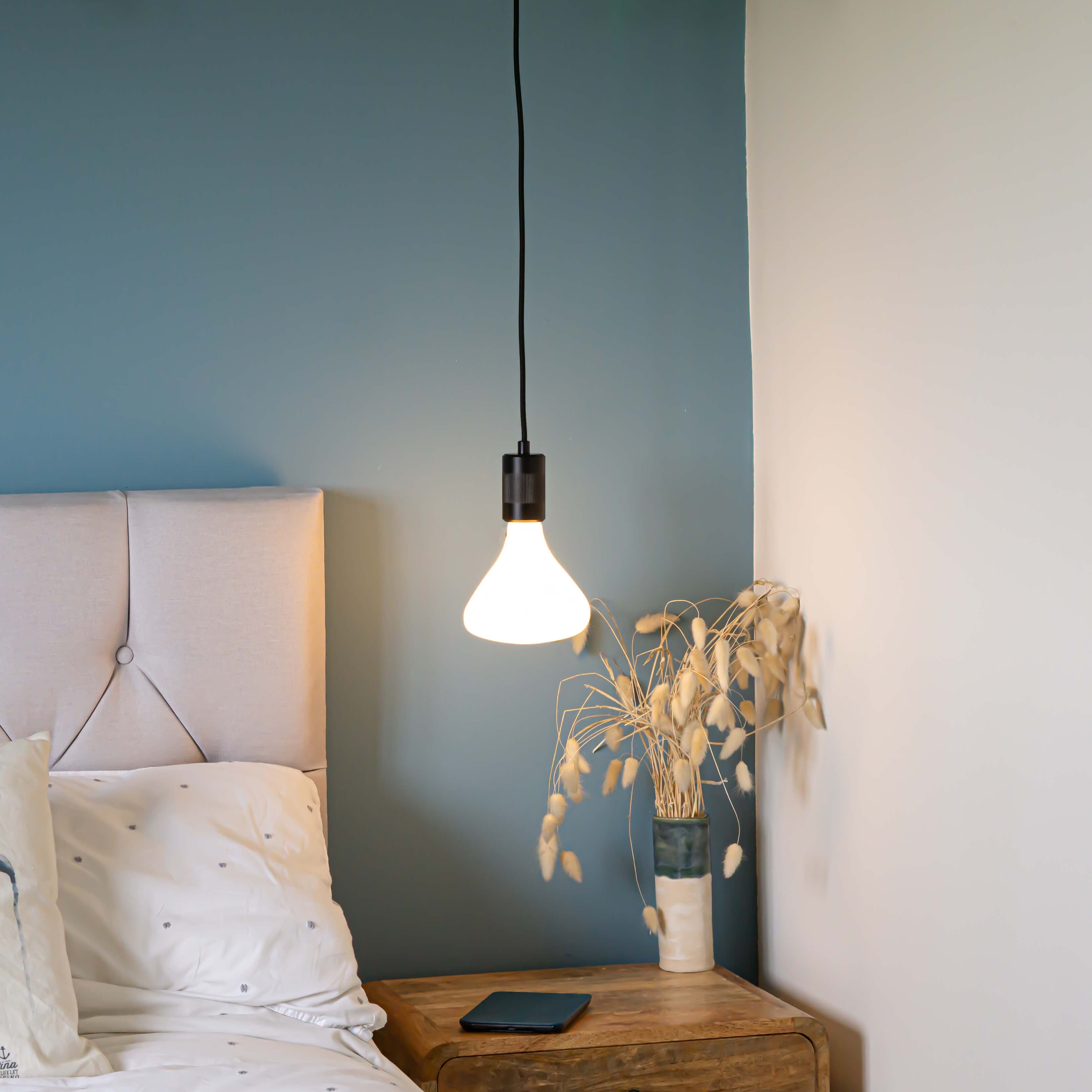 matte black pendant light with astrid bulb hanging above the bedside table