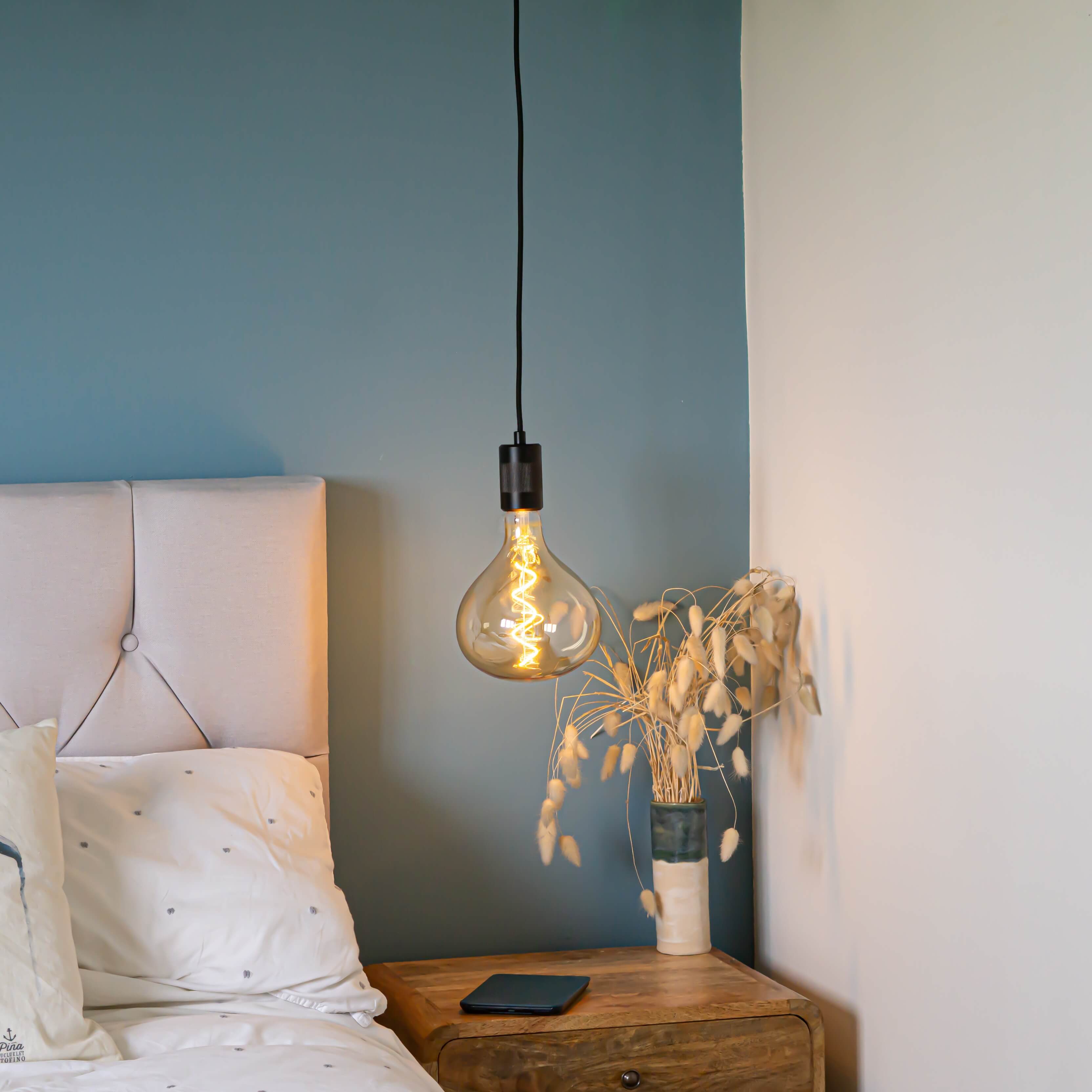 matte black pendant light with olivia bulb hanging above the bedside table
