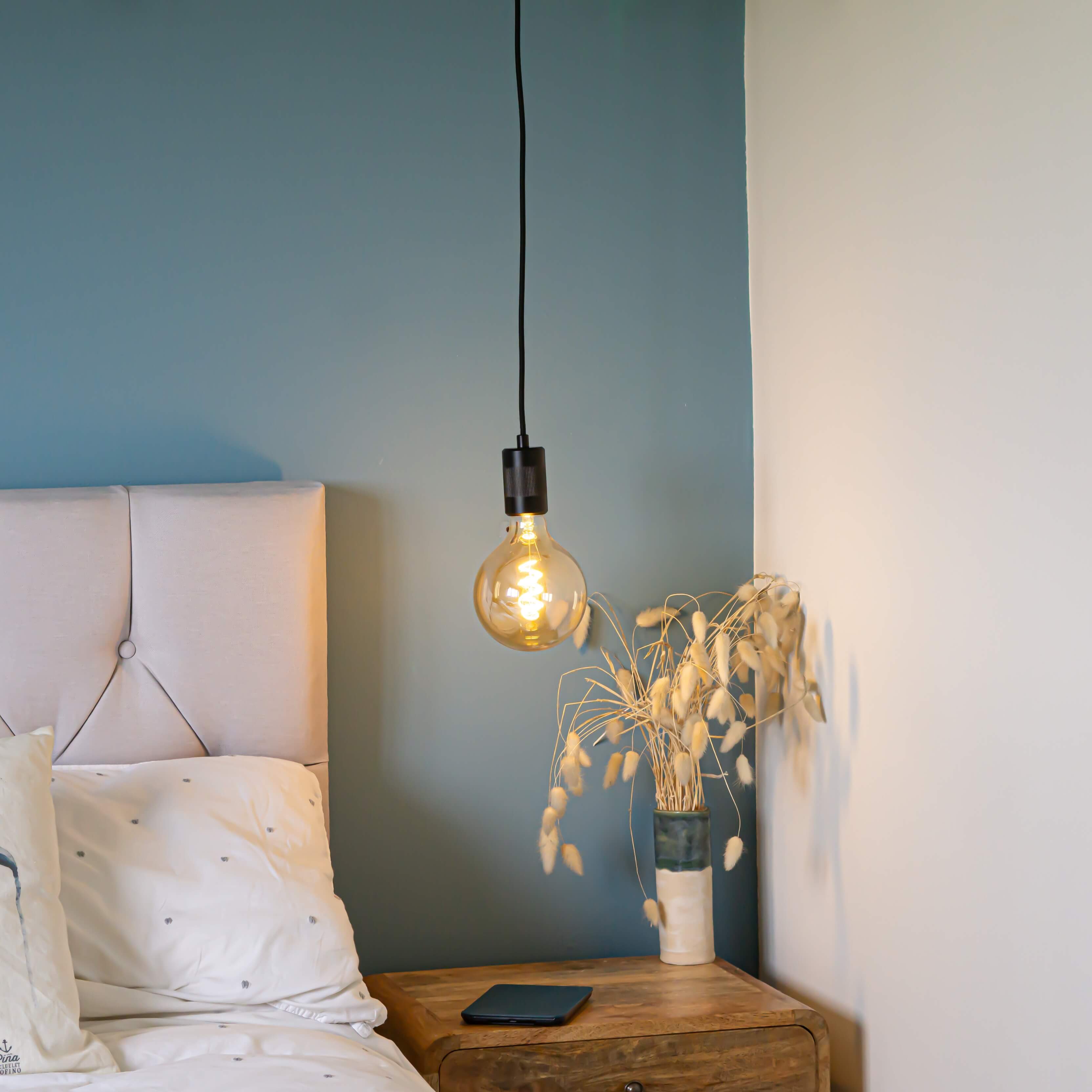 matte black pendant light with sophia bulb hanging above the bedside table