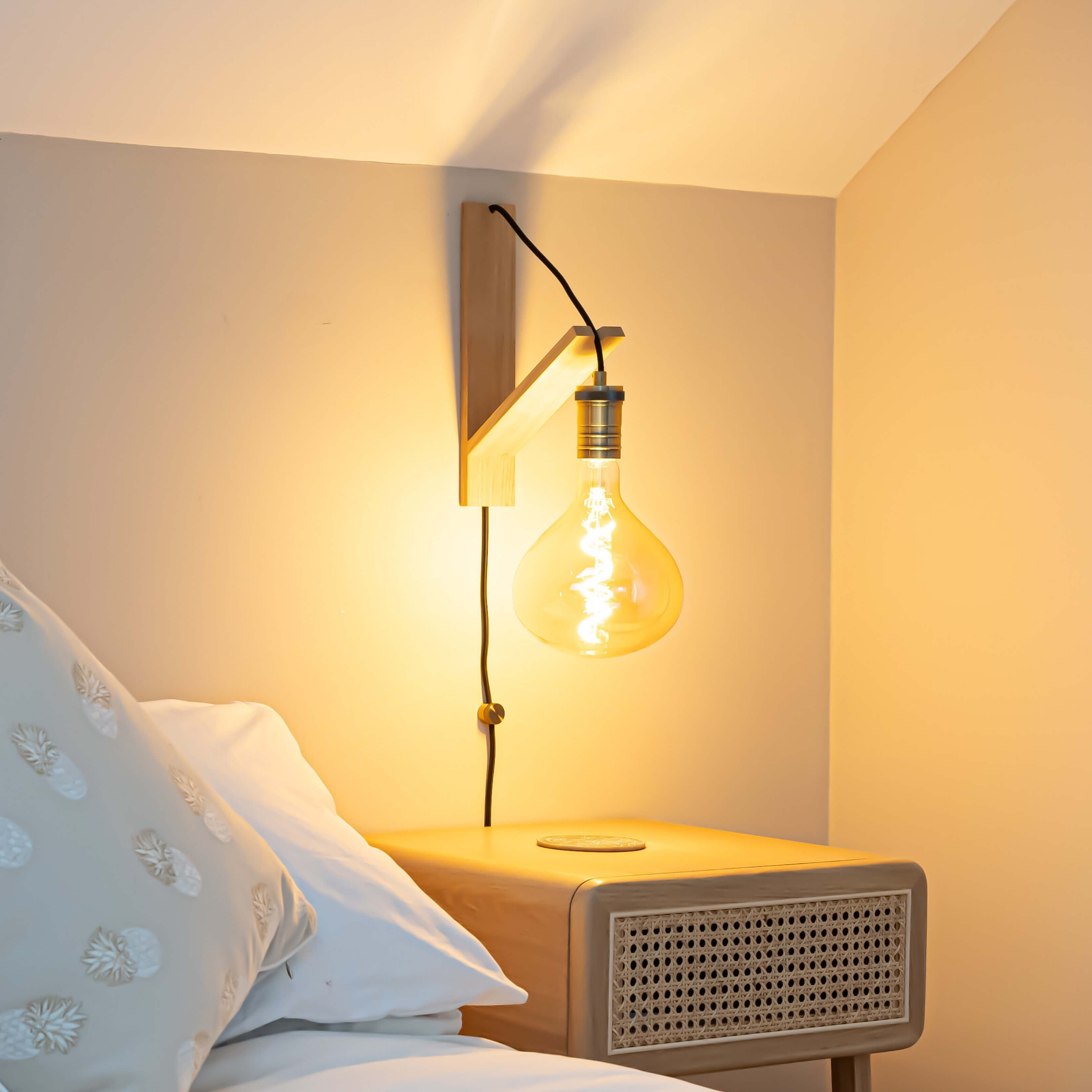 olivia plug in antique brass wall light with straight cable mounted by a bed