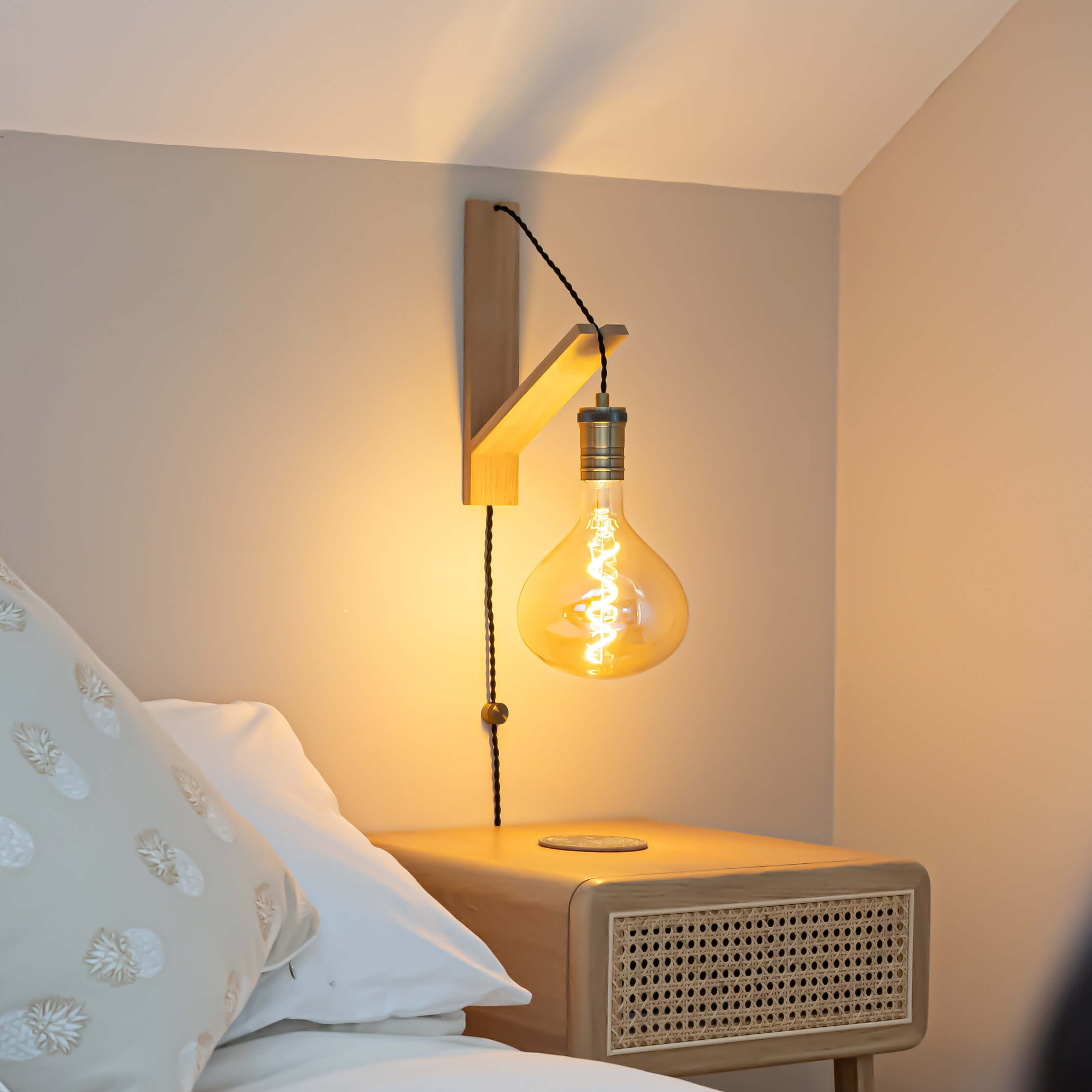 olivia plug in antique brass wall light with twisted cable mounted by a bed