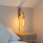 olivia plug in brass wall light with twisted cable mounted by a bed