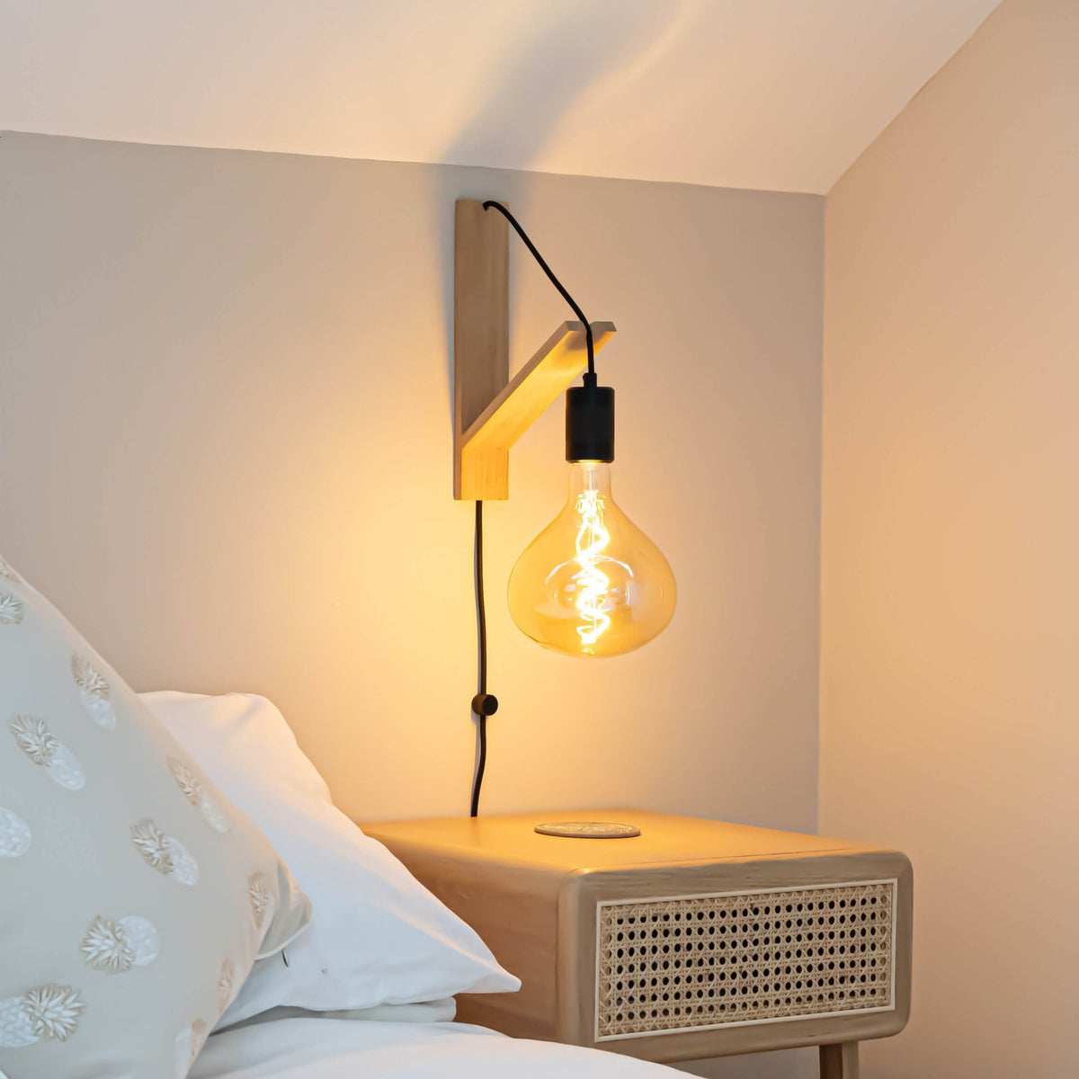 olivia plug in matte black wall light mounted by a bed