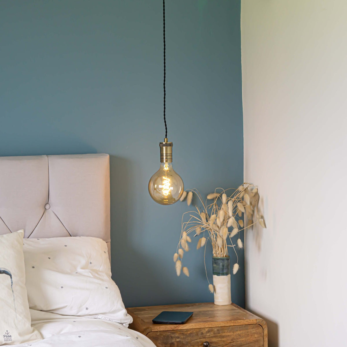antique bronze pendant light and twisted cable with sophia bulb hanging above the bedside table