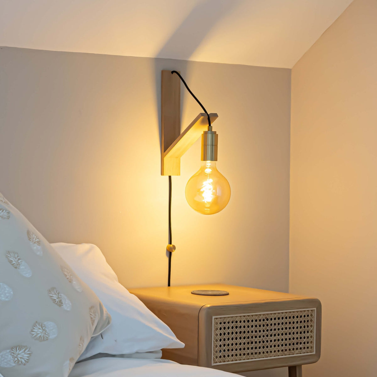 sophia plug in brass wall light with straight cable mounted by a bed