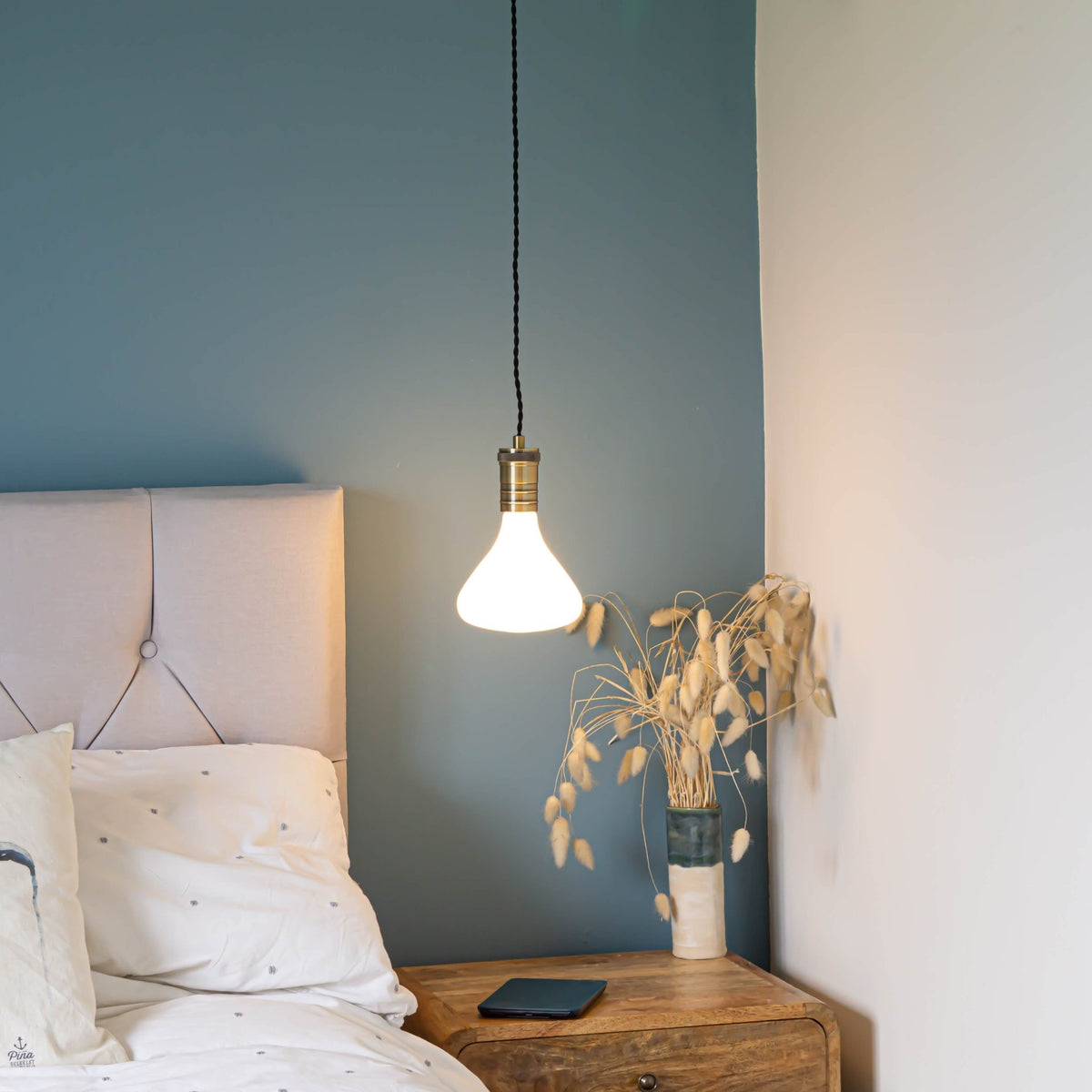 antique bronze pendant light and twisted cable with astrid bulb hanging above the bedside table 