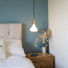 brass pendant light and straight cable with astrid bulb hanging above the bedside table 