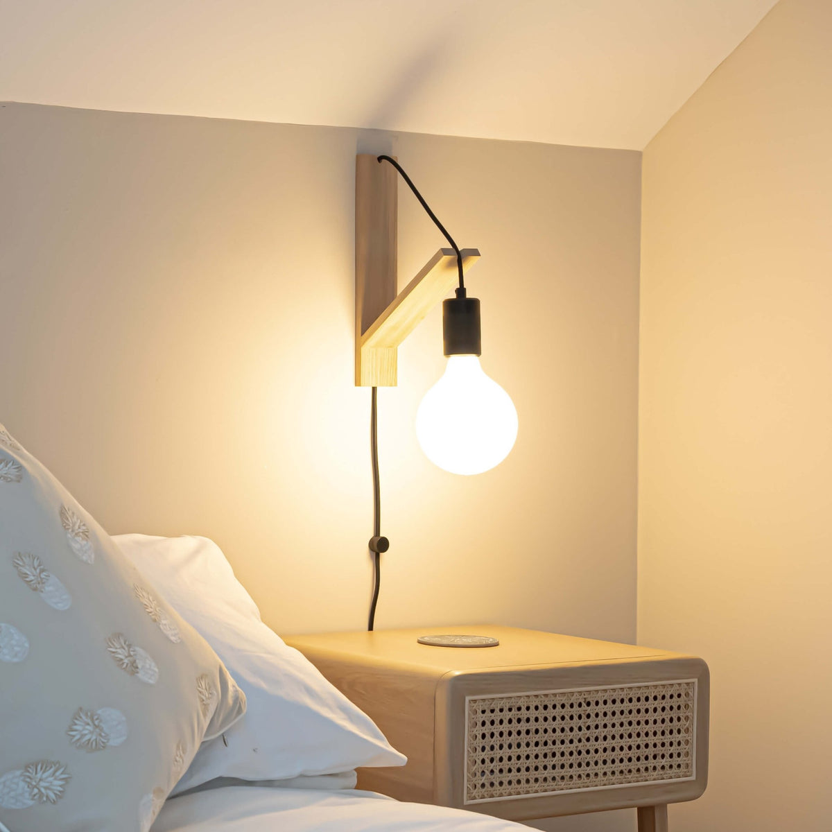 plug in matte black wall light mounted by a bed
