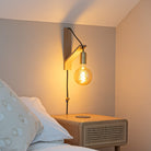 felicity plug in brass wall light with straight cable mounted by a bed