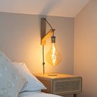 celeste plug in antique brass wall light with twisted cable mounted by a bed