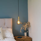 brass pendant light and twisted cable with felicity bulb hanging above the bedside table 