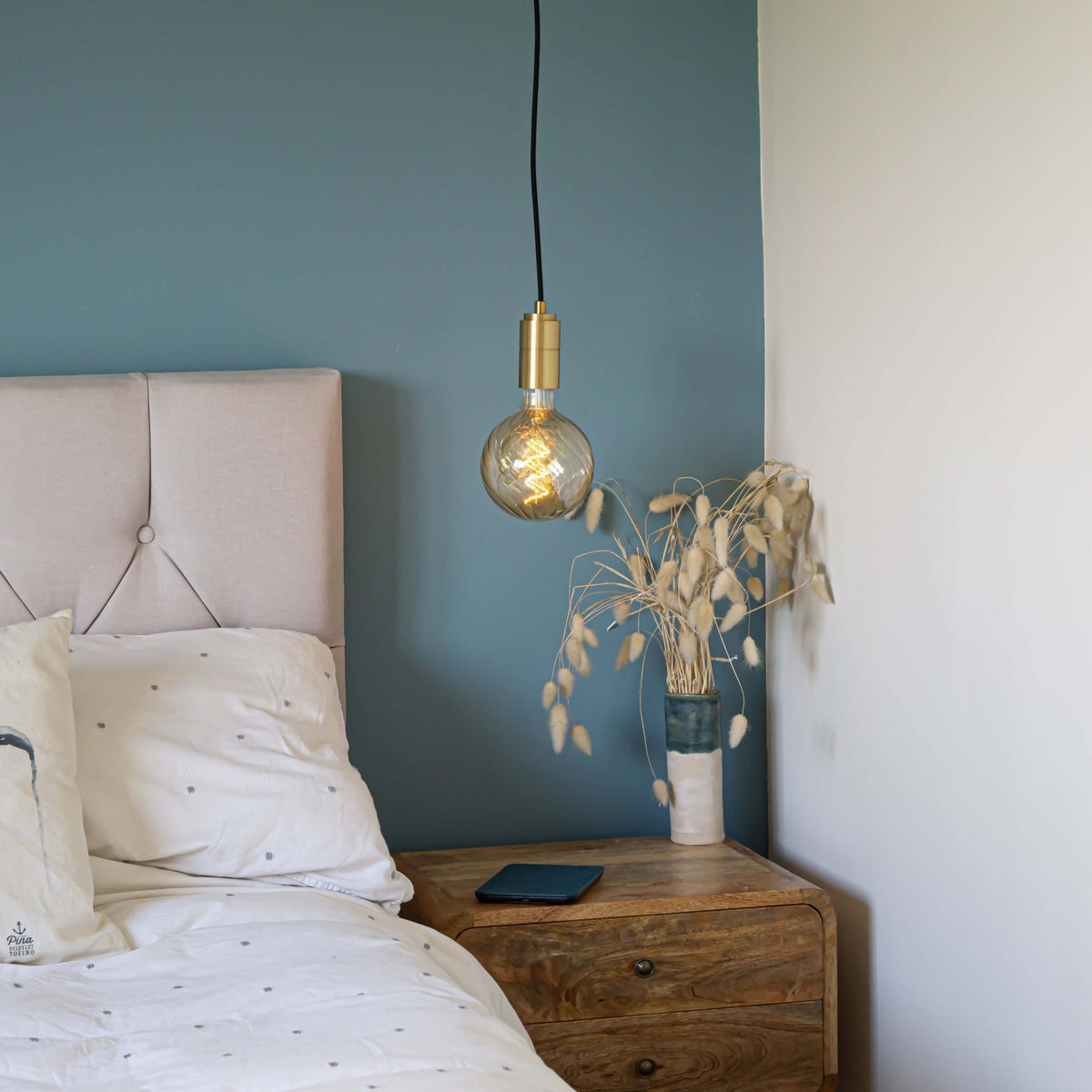 brass pendant light and straight cable with felicity bulb hanging above the bedside table 