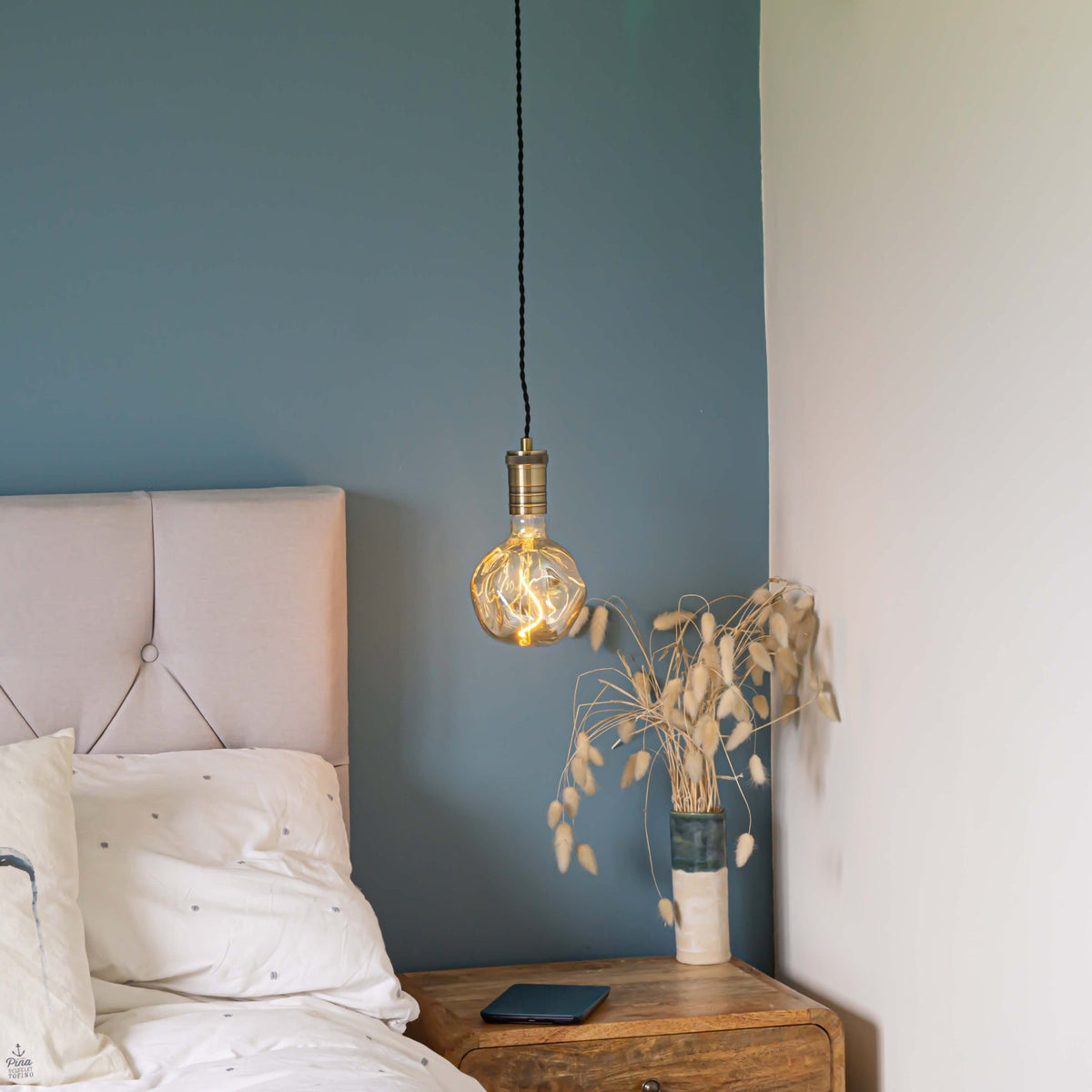 antique bronze pendant light and twisted cable with isabella bulb hanging above the bedside table 