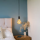 matte black pendant light with isabella bulb hanging above the bedside table 