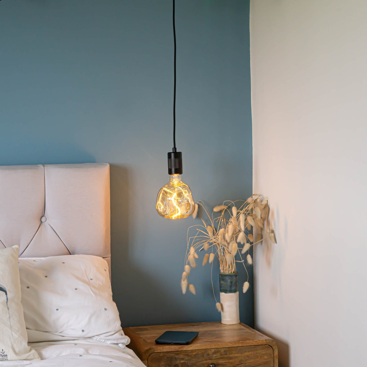 matte black pendant light with isabella bulb hanging above the bedside table 