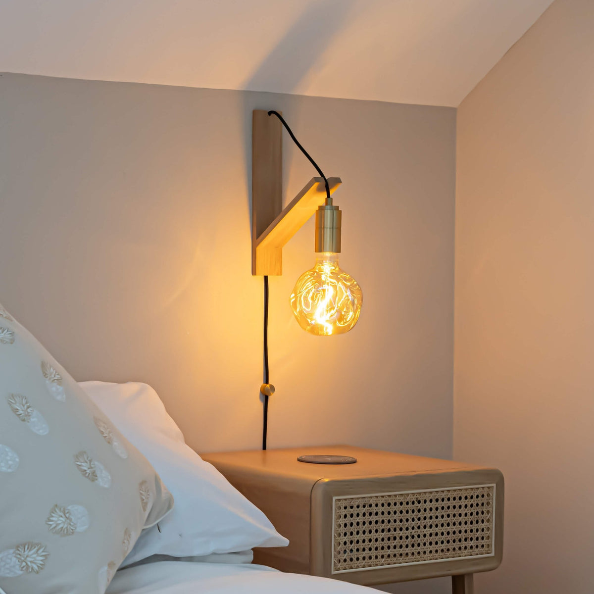 isabella plug in brass wall light with straight cable mounted by a bed