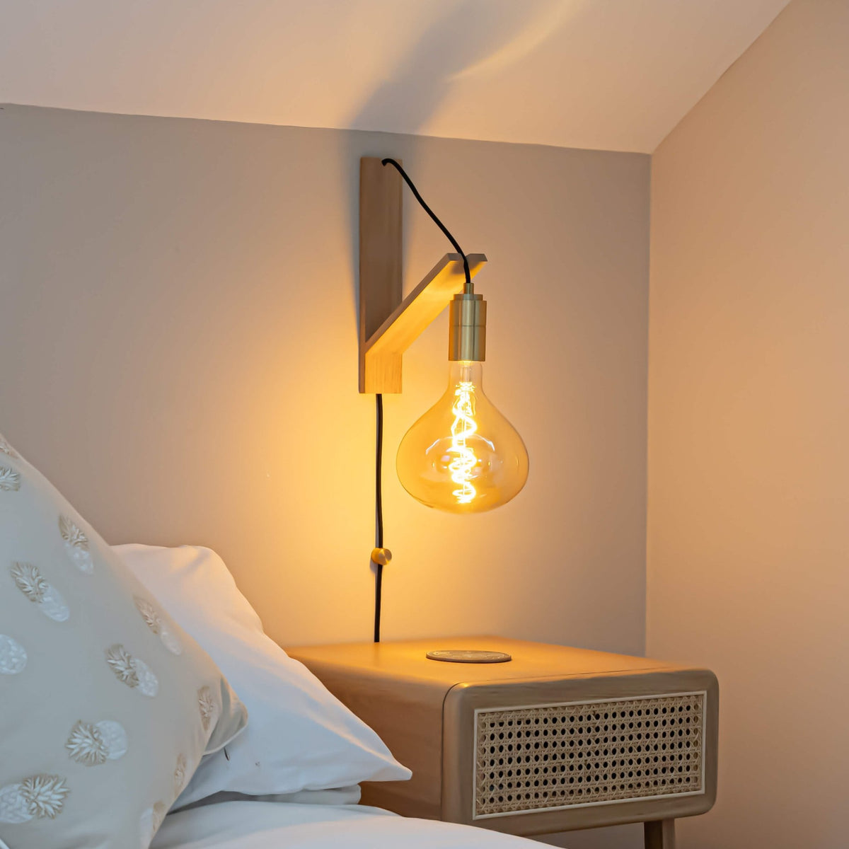 olivia plug in brass wall light with straight cable mounted by a bed