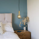 brass pendant light and straight cable with sophia bulb hanging above the bedside table 